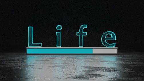 The word 'Life' is displayed in large, glowing teal letters above a horizontal progress bar that is partially filled. The background is dark with a reflective surface below the text and bar, creating a sense of depth and modernity.