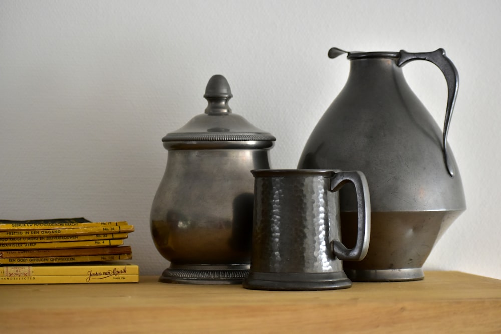 a table topped with a metal pitcher and a stack of books