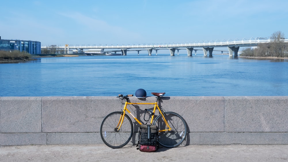 a yellow bicycle parked next to a concrete wall
