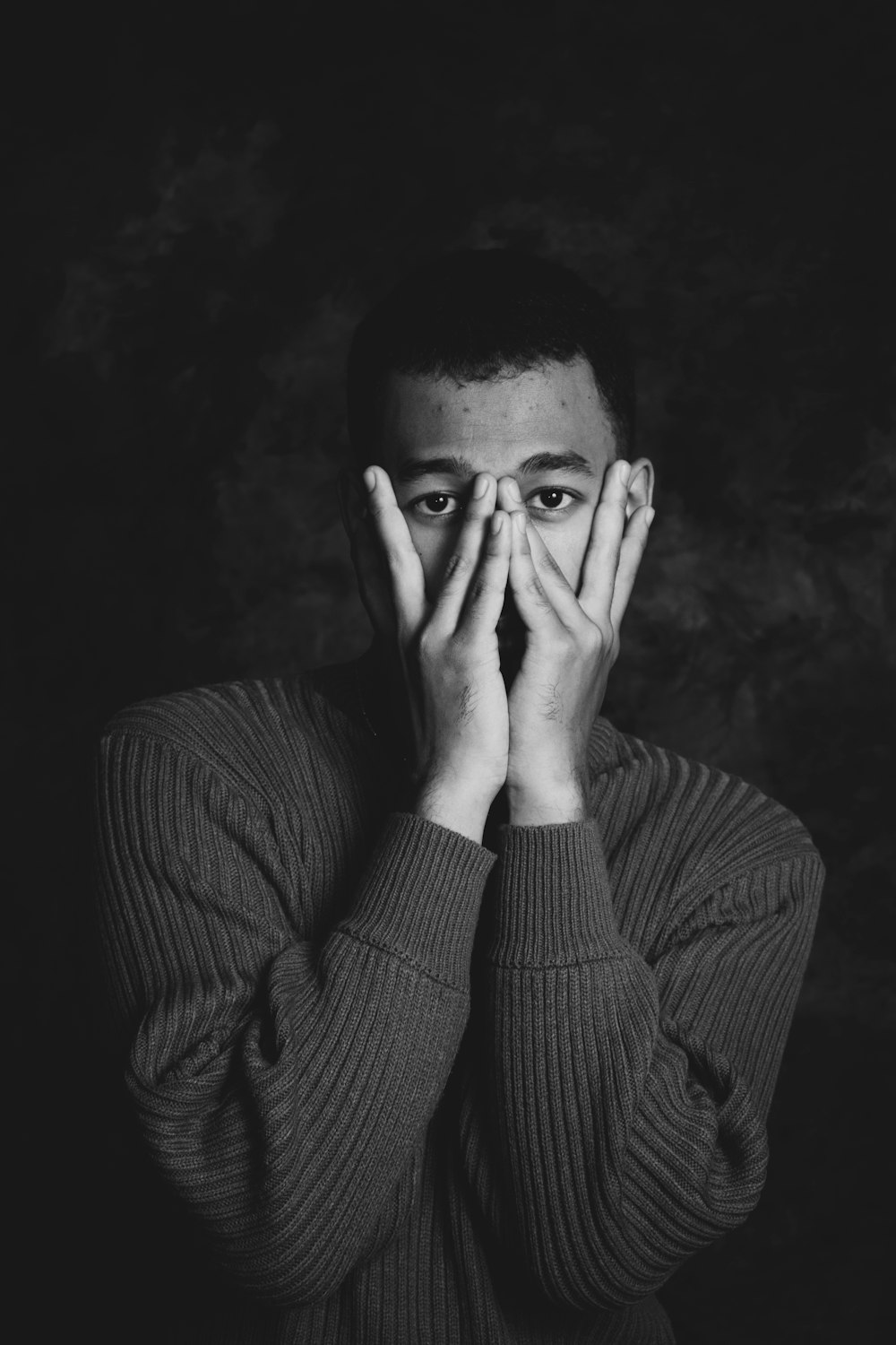 a black and white photo of a man covering his eyes