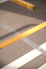 Close-up of a worker painting parking lines with a yellow paint roller on asphalt.