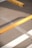 A close-up view of a yellow barrier pole positioned diagonally over asphalt, with part of a parking lot's striped markings visible in the background.