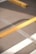 A close-up view of a yellow barrier pole positioned diagonally over asphalt, with part of a parking lot's striped markings visible in the background.