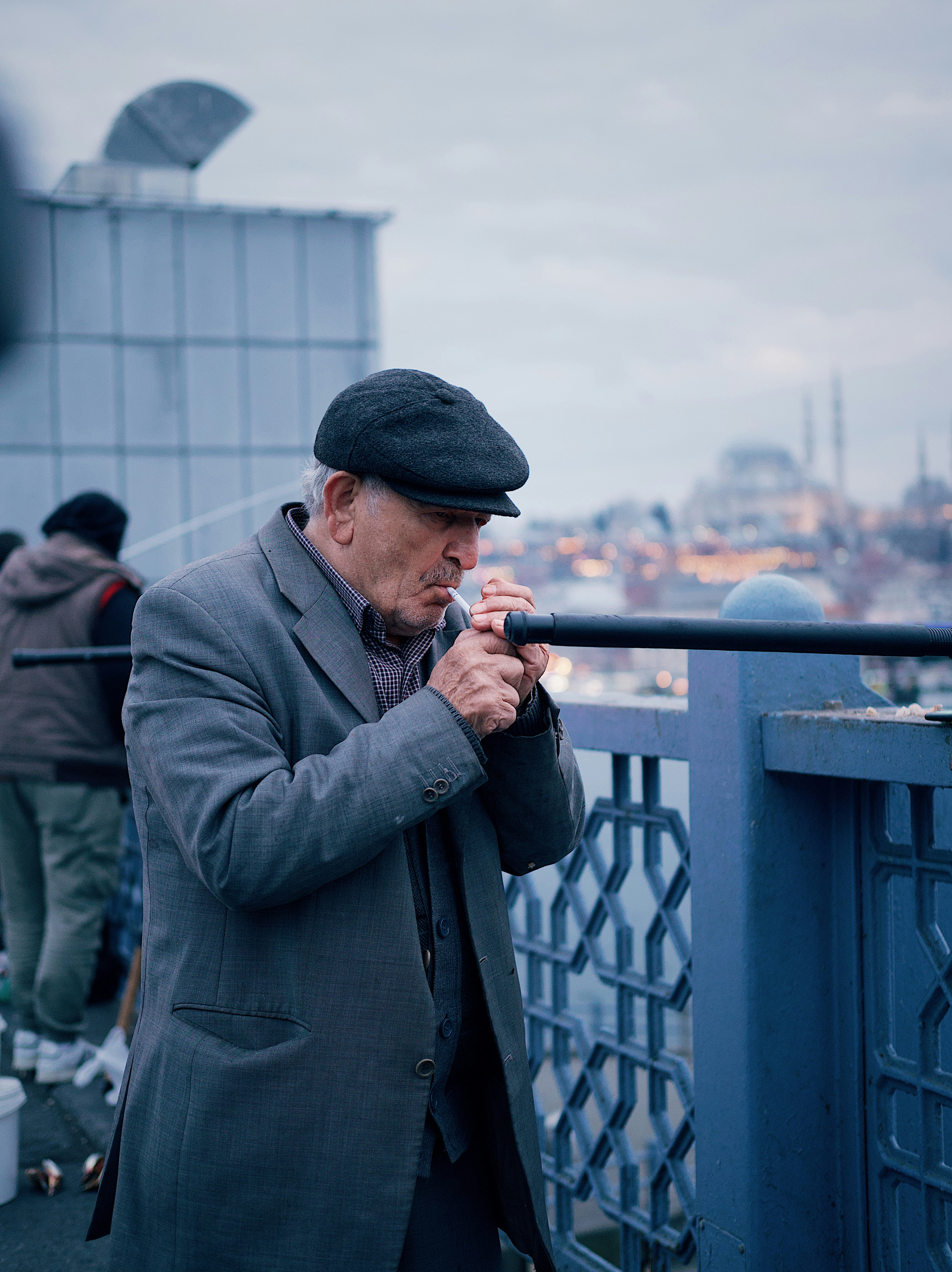 a man standing on a bridge smoking a cigarette