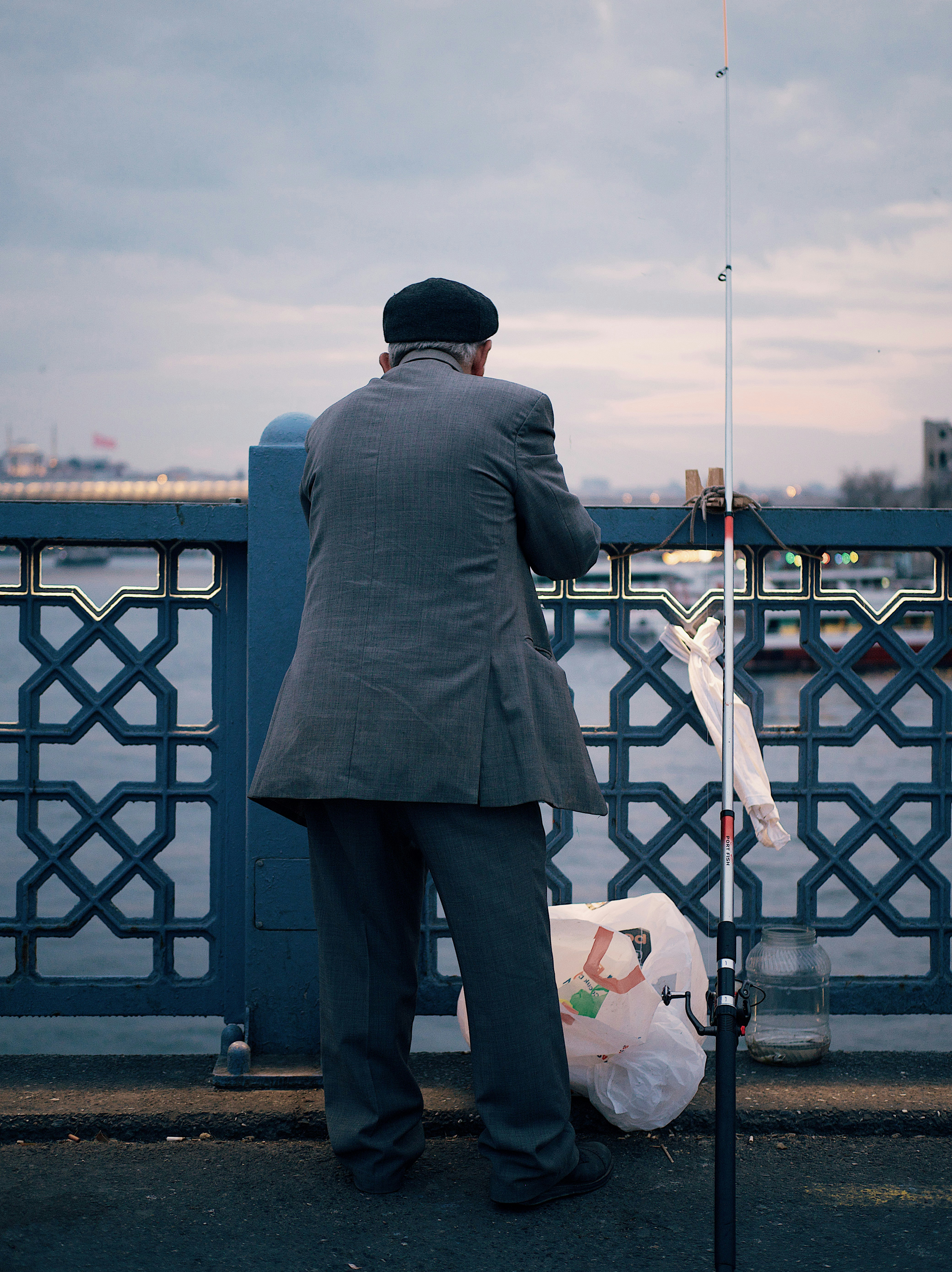 a man in a suit and hat standing next to a fence