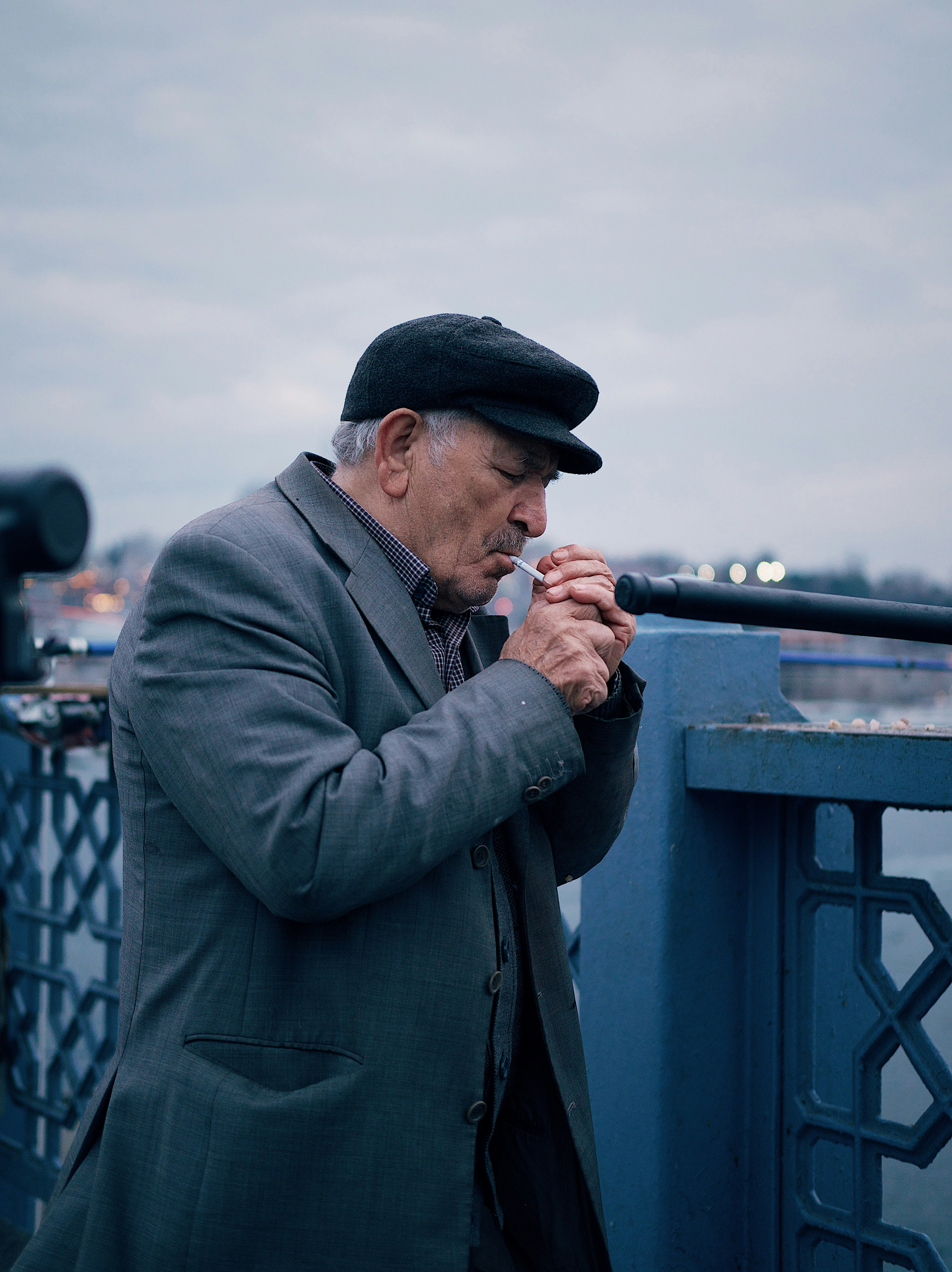 a man standing on a bridge smoking a cigarette