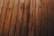 Wooden planks arranged in parallel, displaying a natural grain pattern with knots and varying shades of brown.