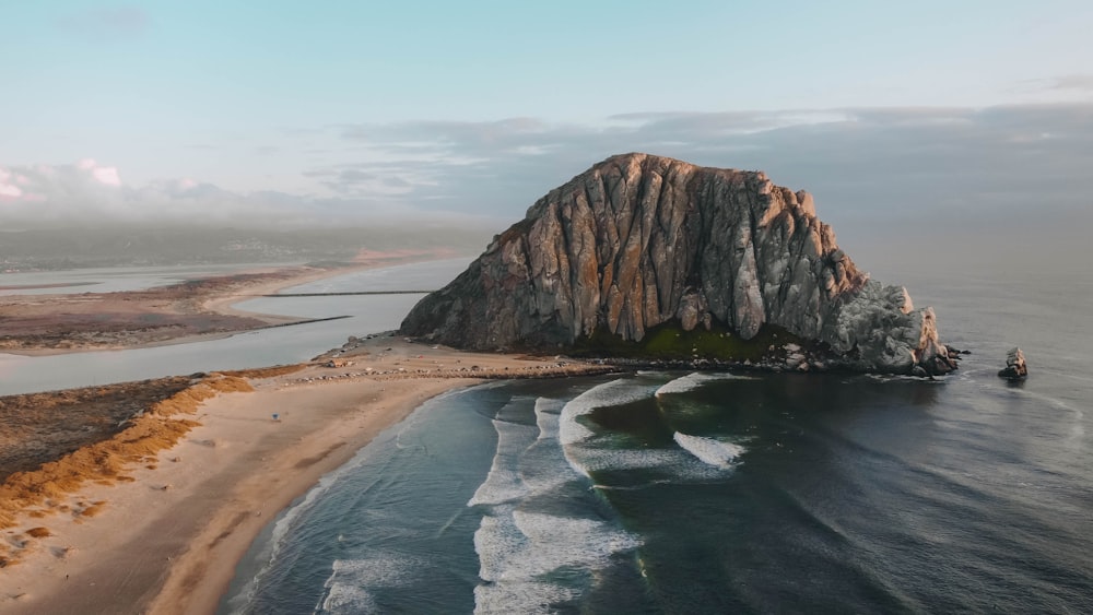 an aerial view of a beach with a large rock