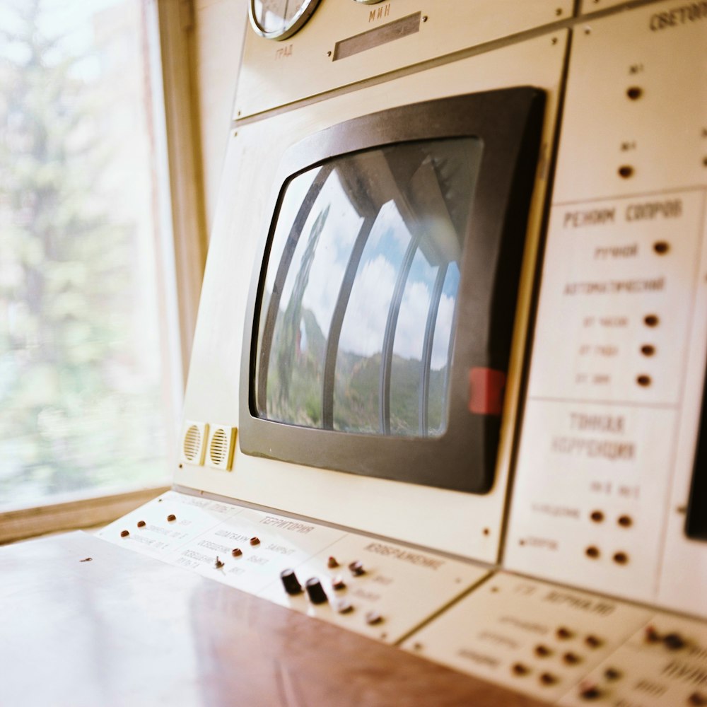 a close up of a washing machine with a reflection of trees in the window