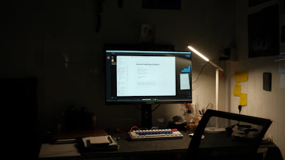 A clean desk setup showing a laptop with an open digital guide on maintenance KPIs against a dark navy background.