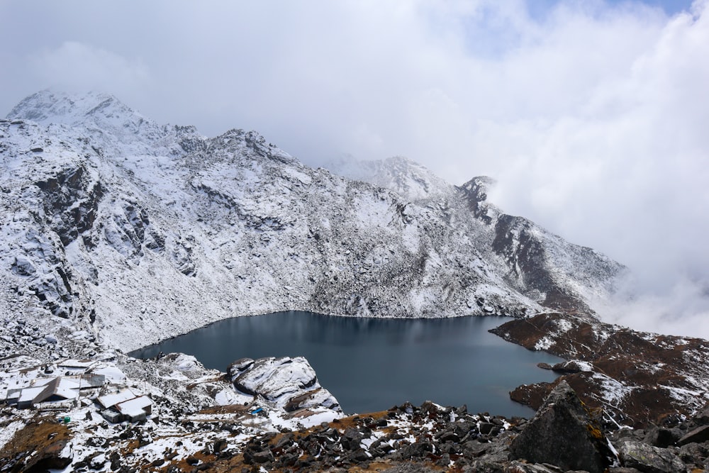 a snow covered mountain with a lake surrounded by rocks