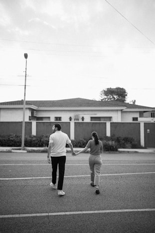 A candid shot of a couple walking hand in hand along a tree-lined street.