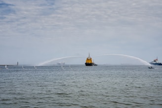 a large yellow boat spraying water on a large body of water