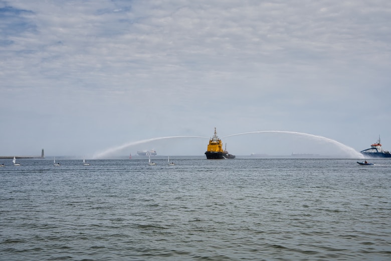 a large yellow boat spraying water on a large body of water