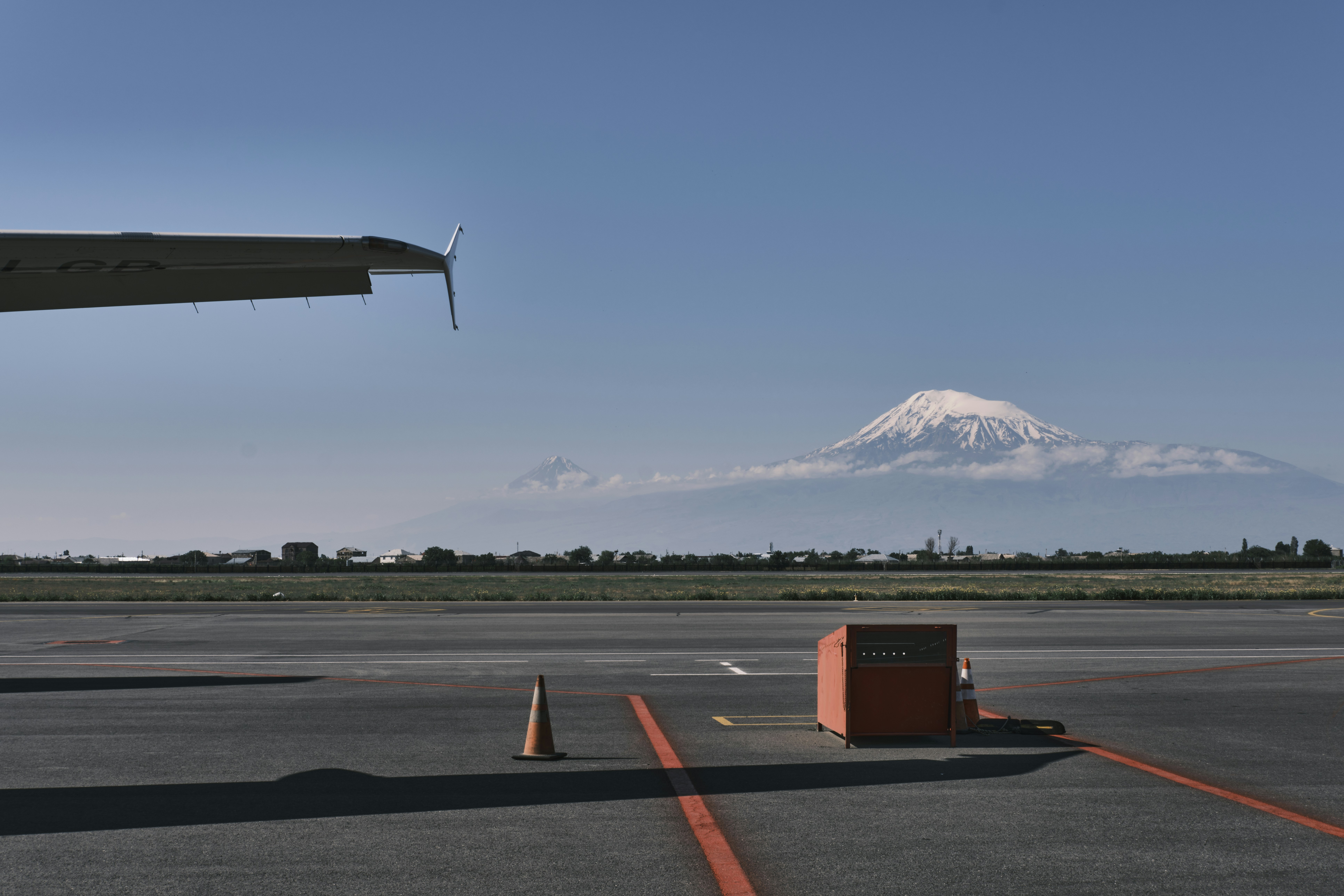 a plane is parked on the tarmac with a mountain in the background, 