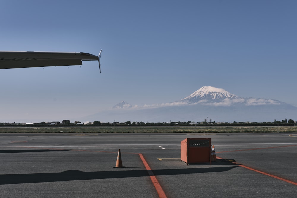 a plane is parked on the tarmac with a mountain in the background