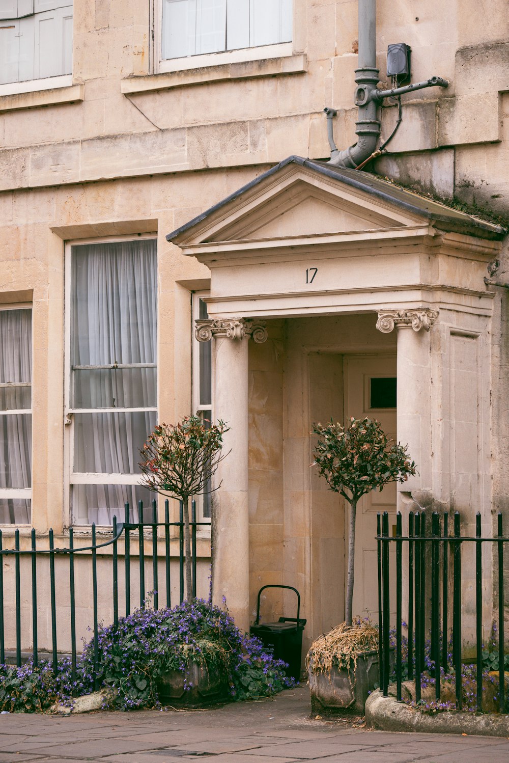 a building with a black fence and a potted tree in front of it