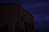 Exterior view of a large warehouse featuring installed surveillance and alarm systems at dusk.