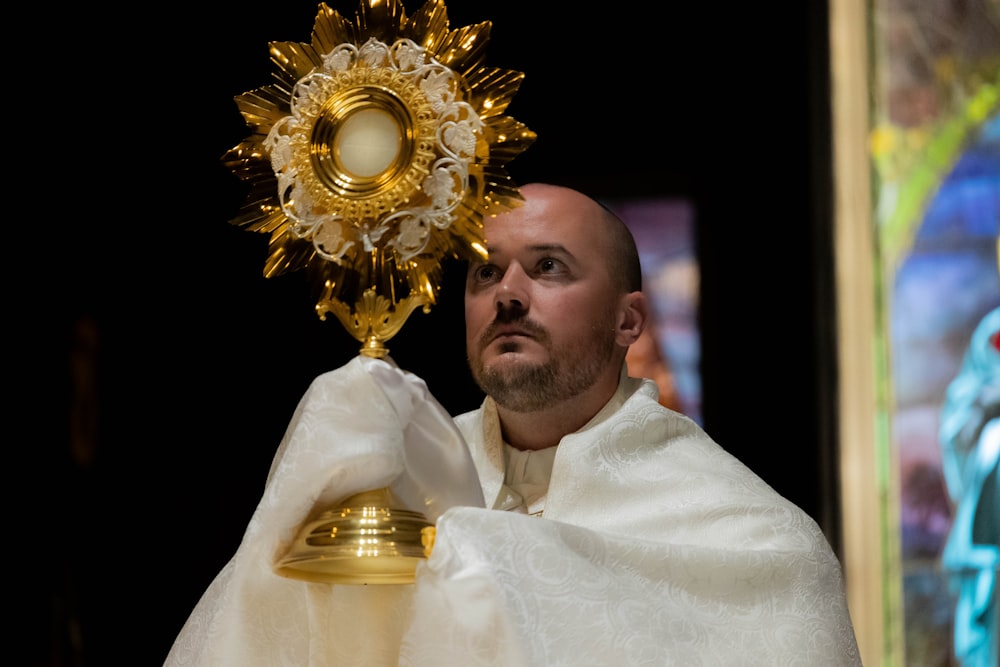 a man in a white robe holding a golden bell