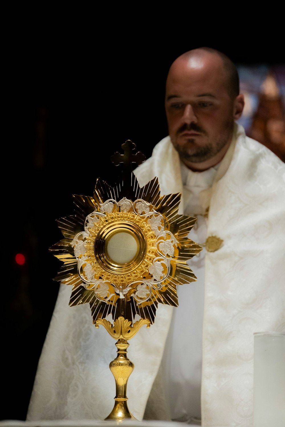 a man in a priest's robes holding a golden cross