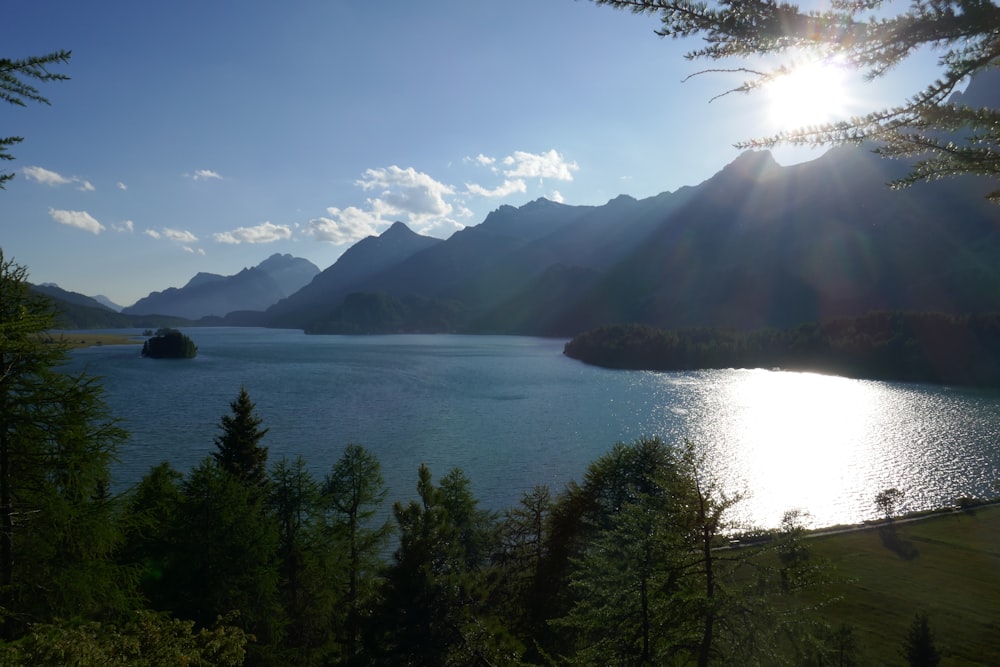 the sun is shining over a lake surrounded by mountains