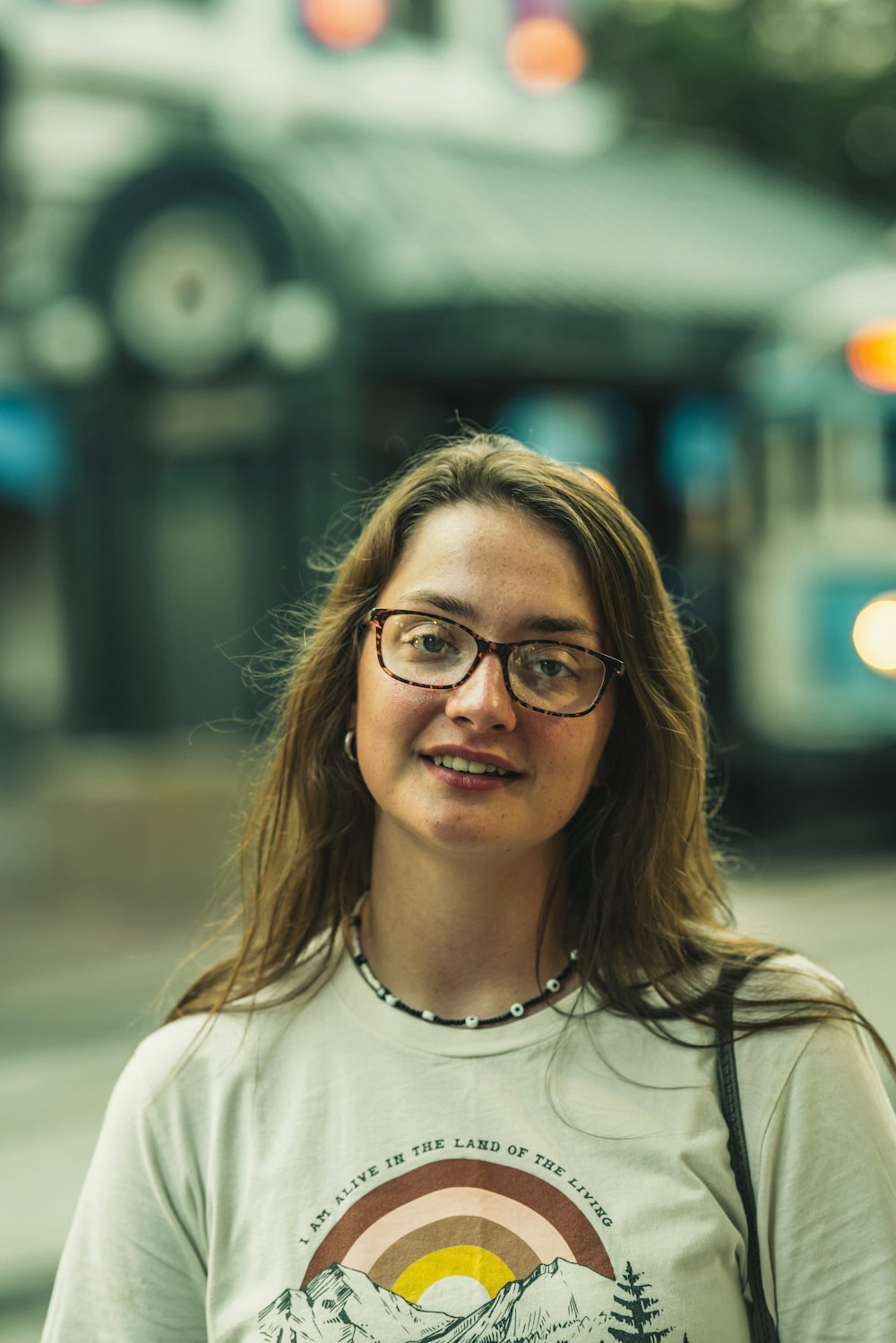 a woman with glasses standing in front of a bus