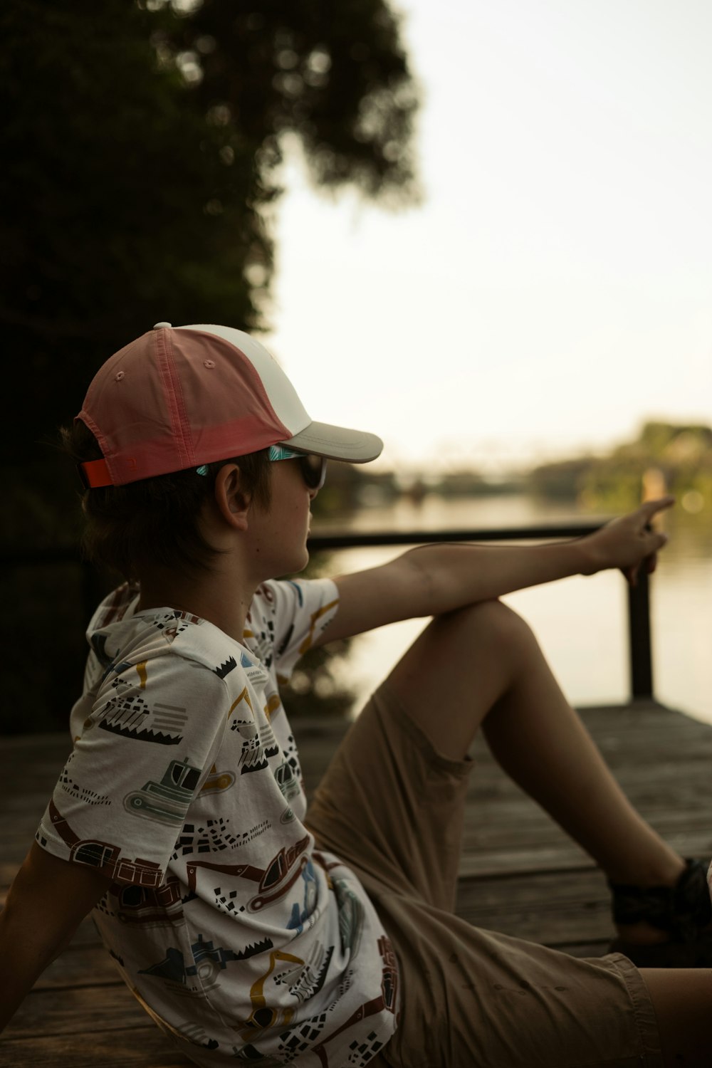 a young boy sitting on a dock with a skateboard