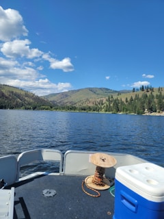 A summer boat day scene with a packed cooler, fishing gear, and sun hats on a sparkling lake.