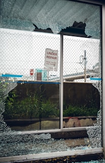a broken glass window with a sign on it