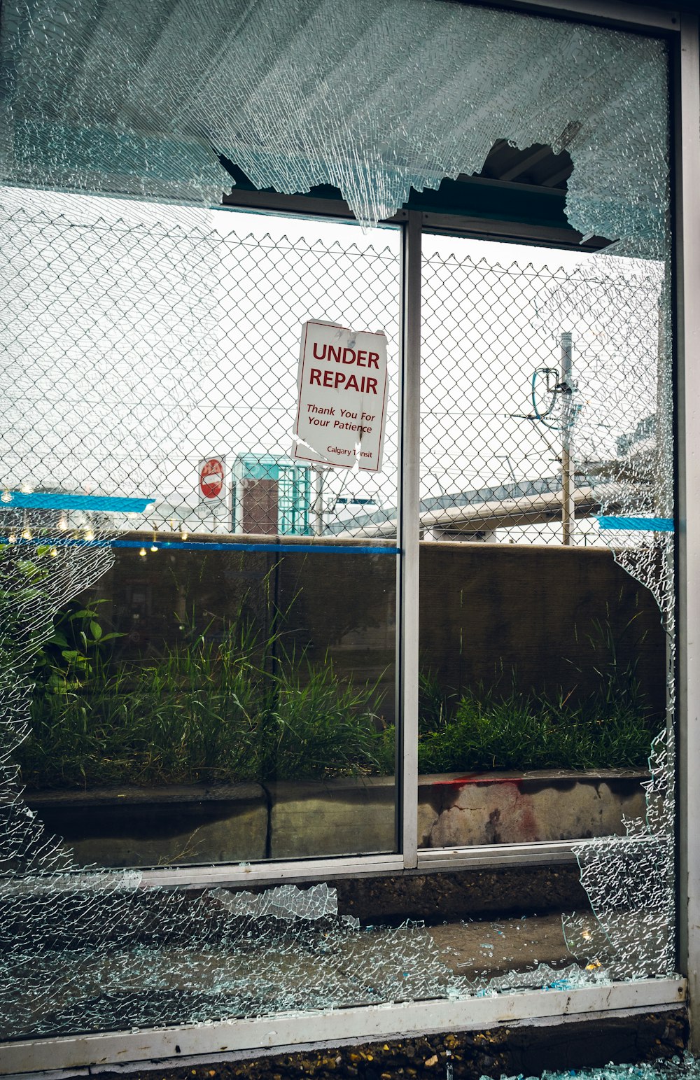 a broken glass window with a sign on it