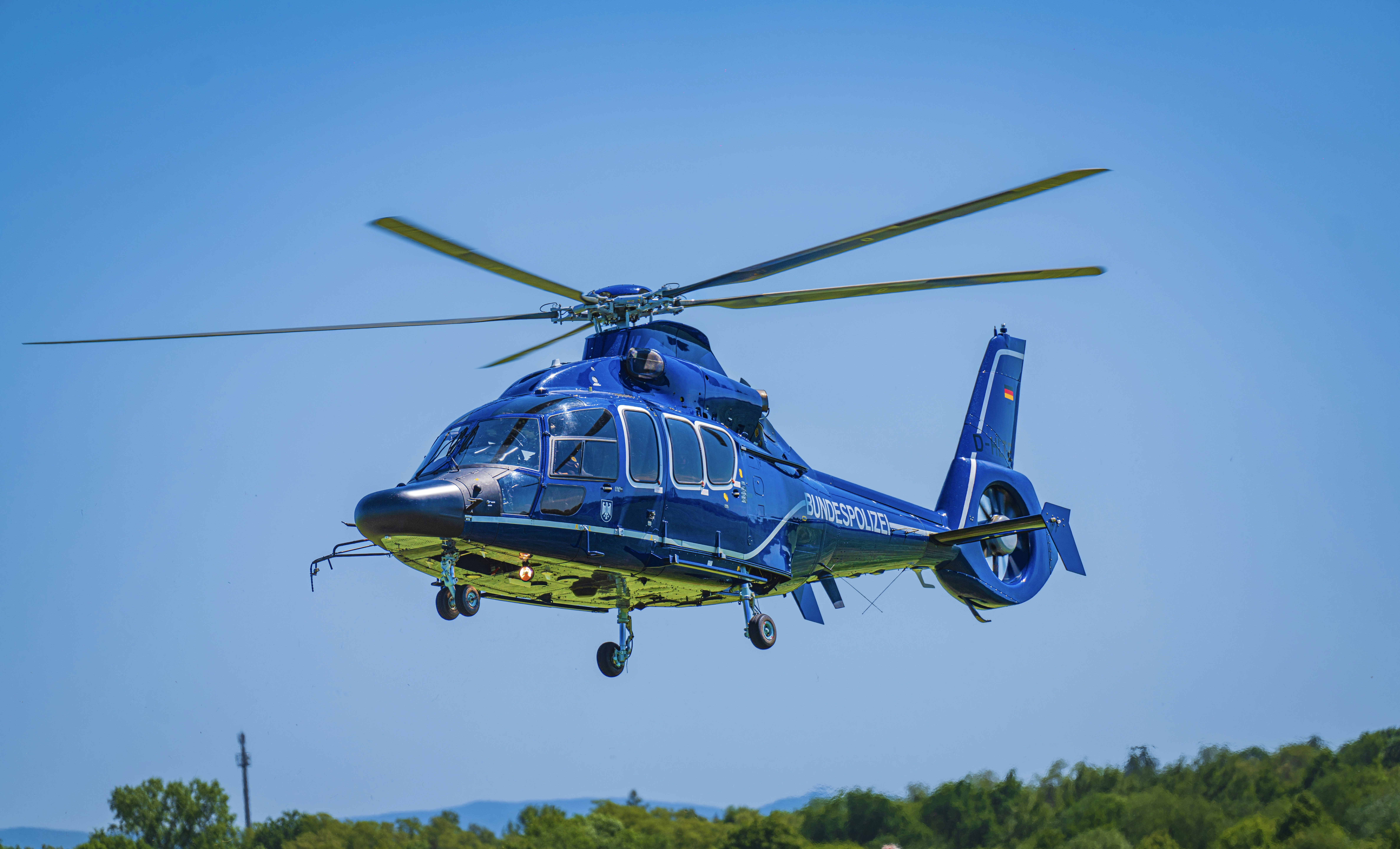 a blue helicopter flying through a blue sky