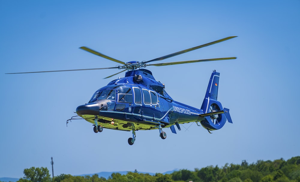 a blue helicopter flying through a blue sky
