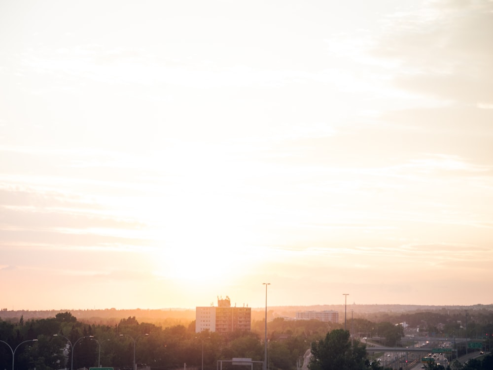 the sun is setting over a city with tall buildings