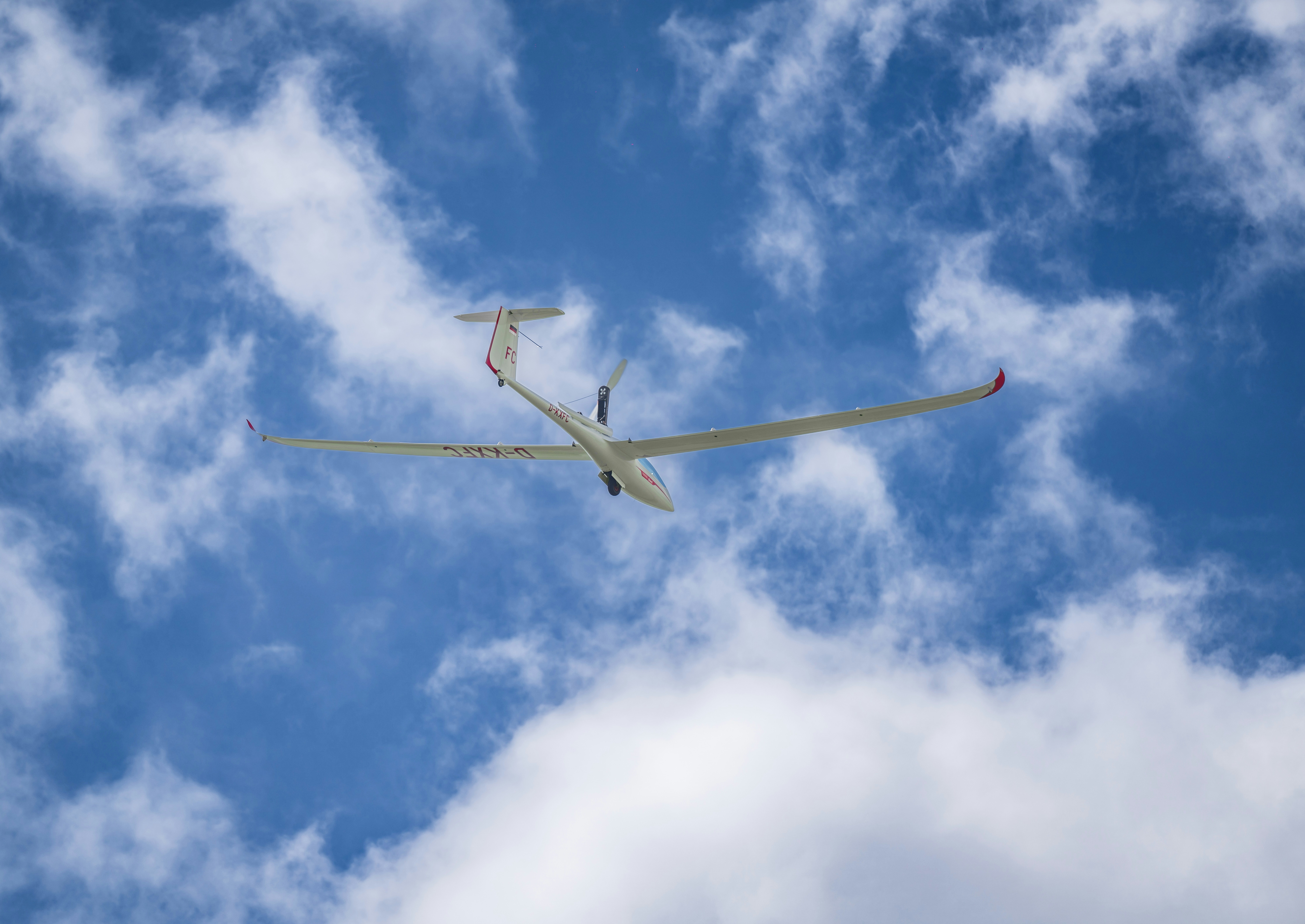 a plane flying through a cloudy blue sky
