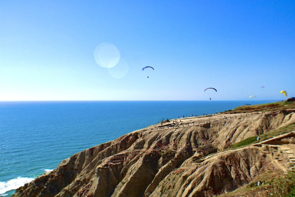 a group of people flying kites over the ocean