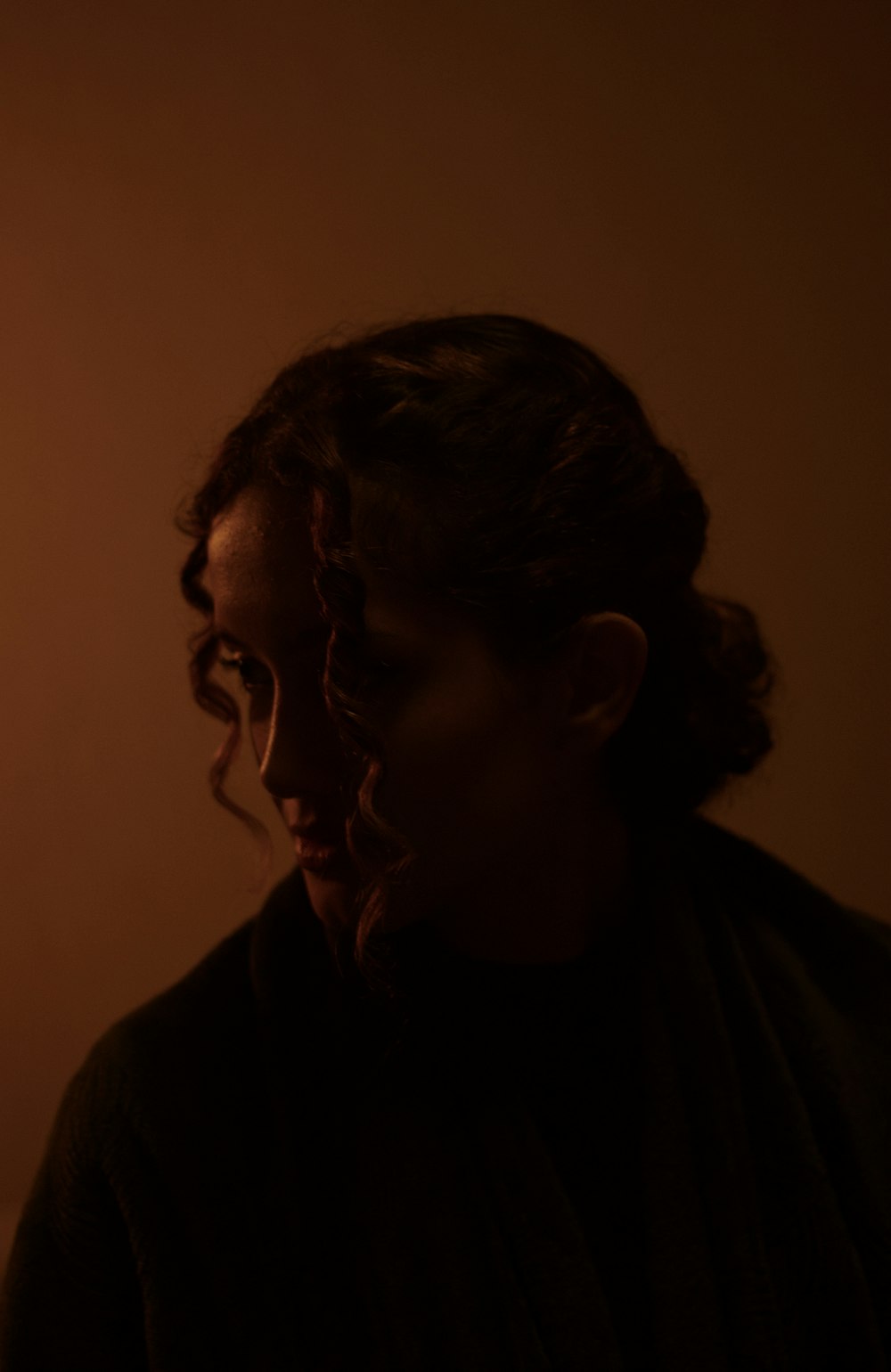 uma mulher em pé em um quarto escuro com os olhos fechados