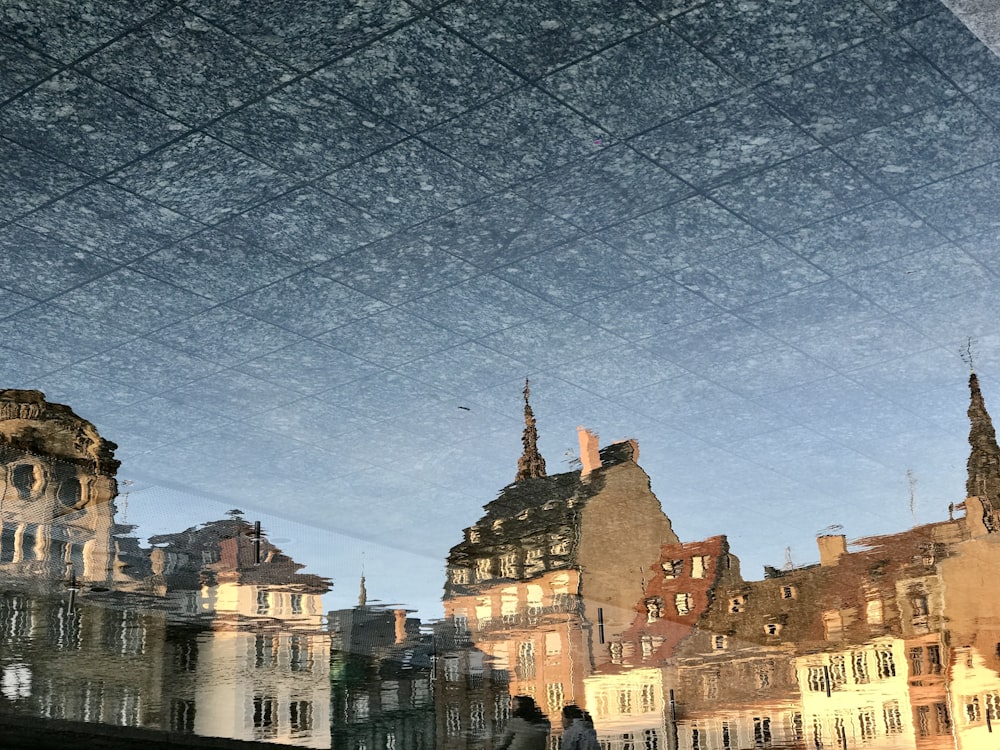 a reflection of buildings in a puddle of water