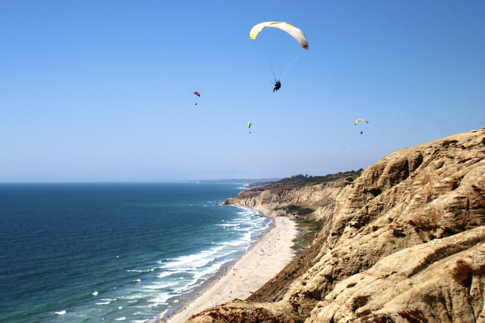 a group of people flying kites over the ocean