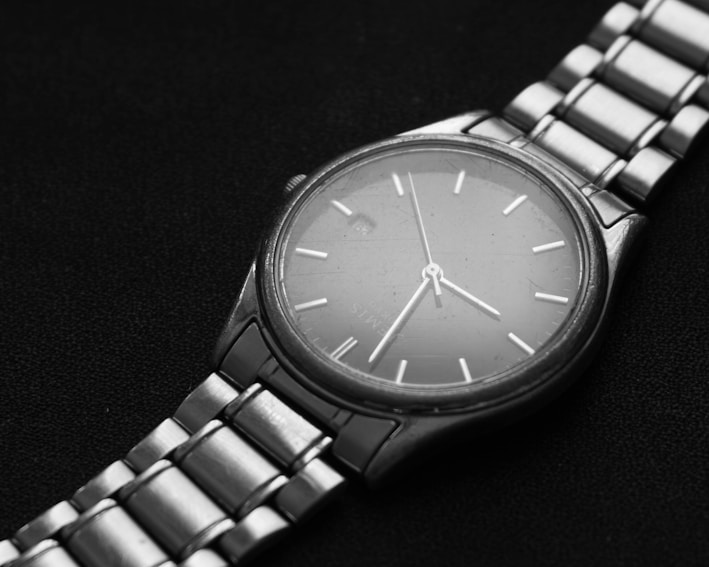 Close-up of a sleek black and gold wristwatch on a minimalist black background