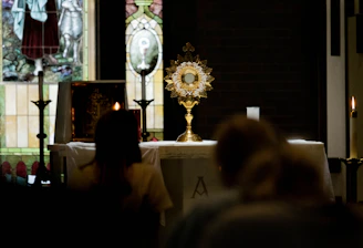 A golden monstrance glowing softly against a dark royal purple velvet backdrop inside a cathedral.