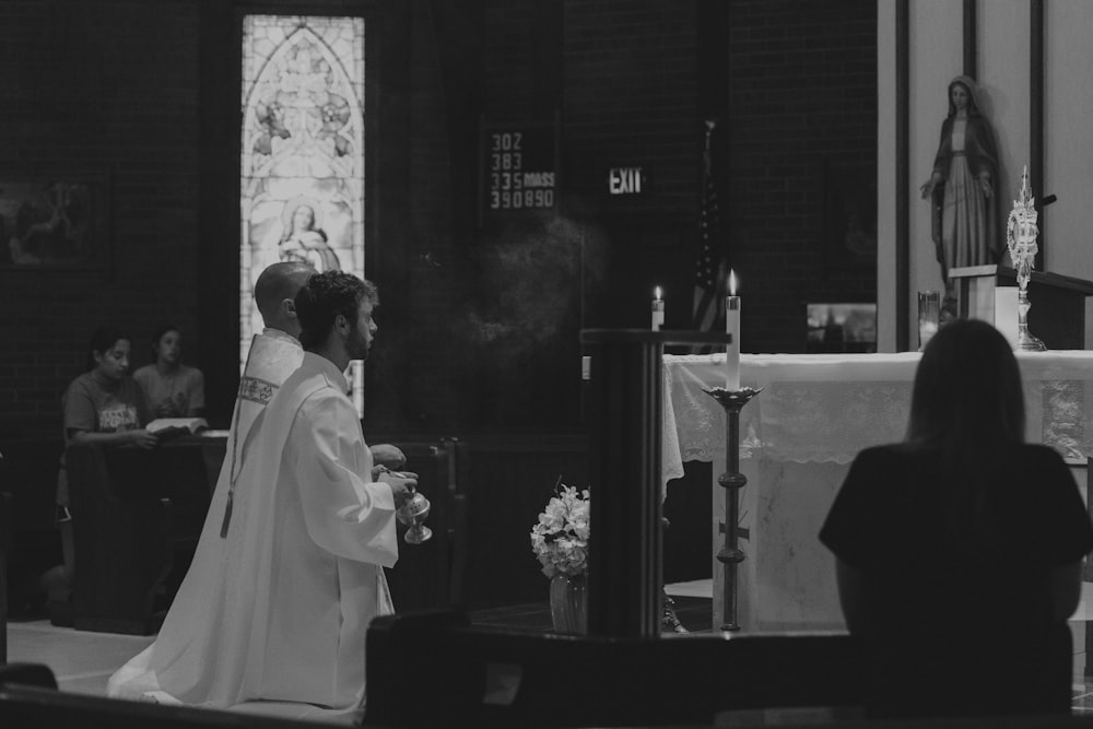 a black and white photo of a priest in a church