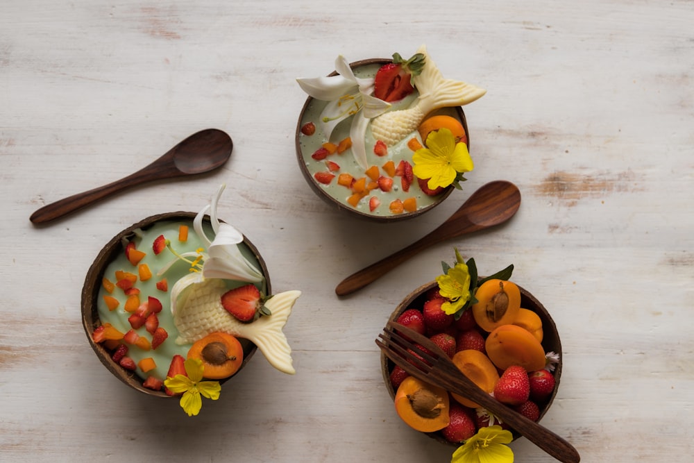 three bowls of food with spoons on a table