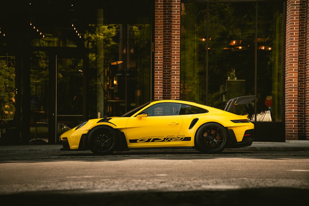 a yellow sports car parked in front of a building