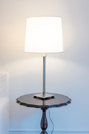 A modern minimalist lamp placed on a wooden table with soft lighting.
