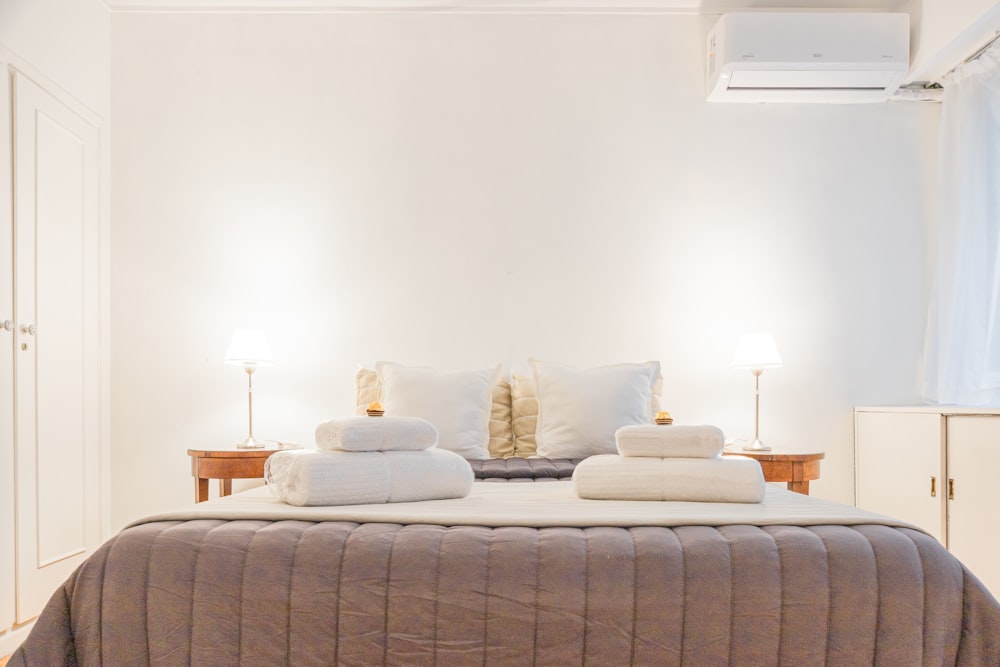 a bed with white sheets and pillows in a bedroom