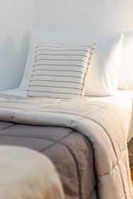 a bed with a white comforter and two pillows