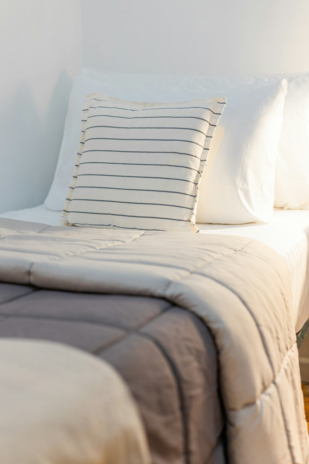 a bed with a white comforter and two pillows