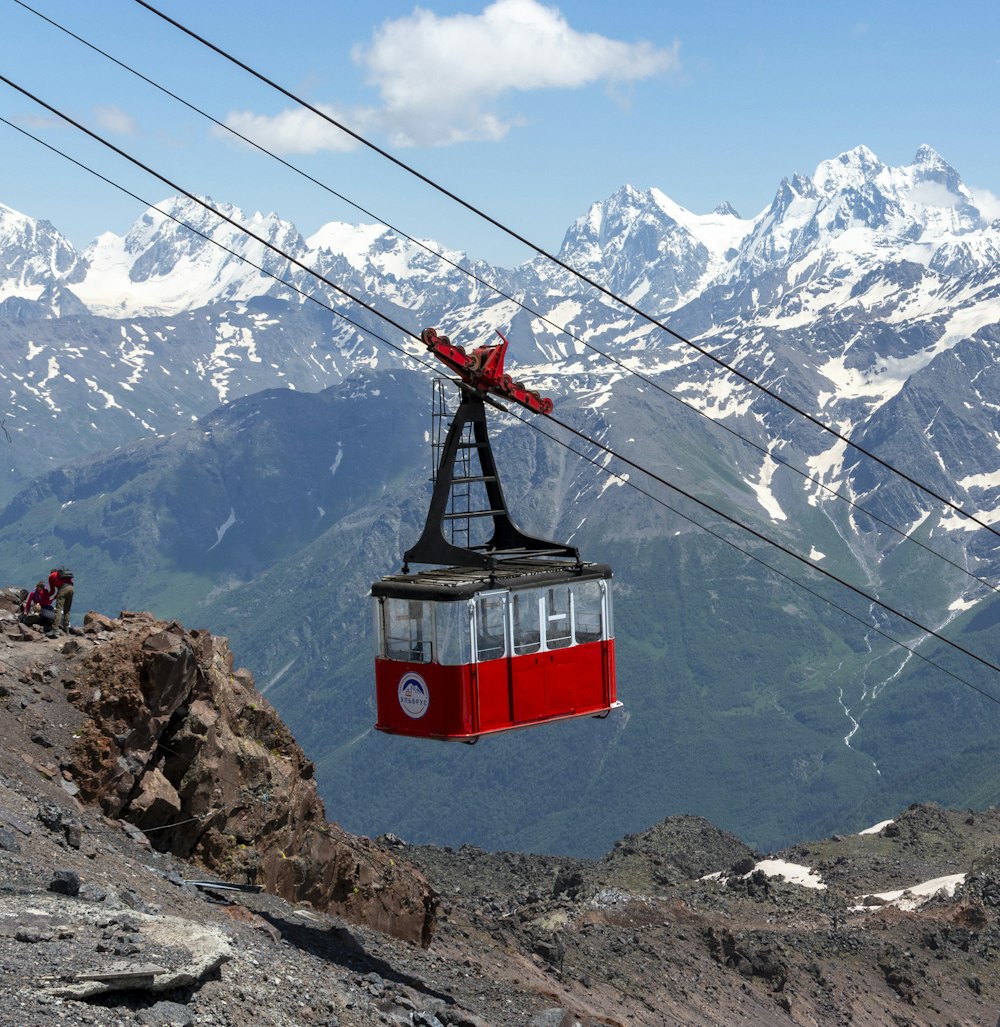 a red cable car going up a mountain side