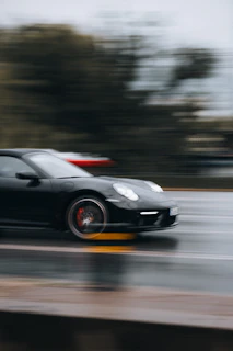 A dynamic shot of a car speeding on a wet road, showcasing the grip of high-performance tires.