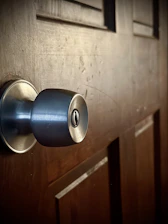 Close-up of hands fitting a new door handle on a wooden door with natural light.